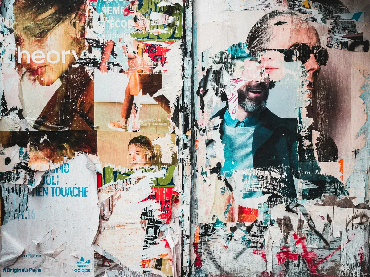 A wall covered in overlapping, brightly coloured posters. Photo by Mika Ruusunen on Unsplash.